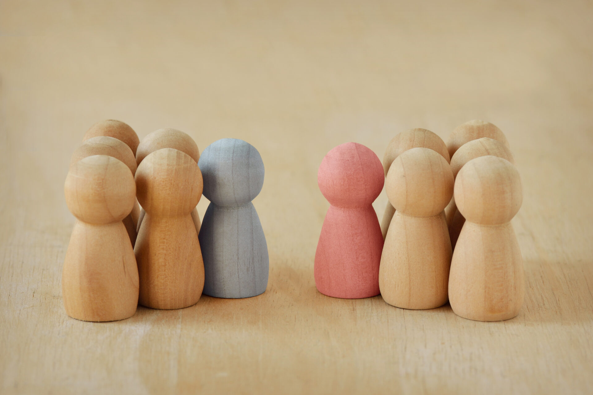 Two groups of wooden pawns with male and female leader facing each other Concept of competition and male vs female leadership